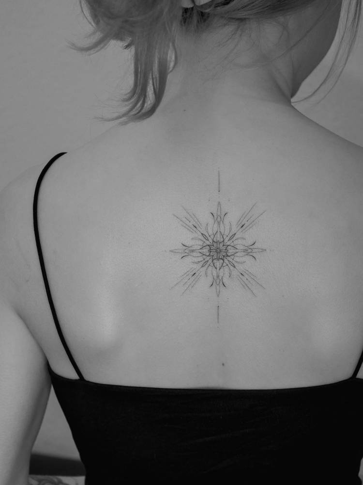 Ornamental design in fine line style tattooed on the upper back.