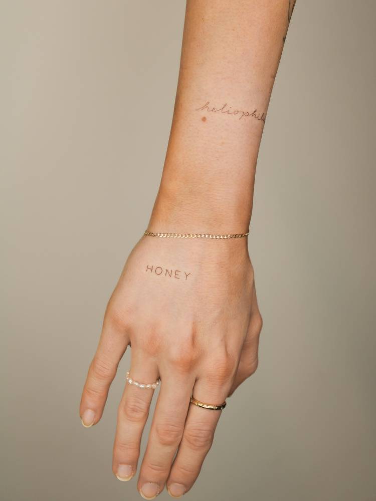 Lettering tattoo of the word "honey" located on the hand.