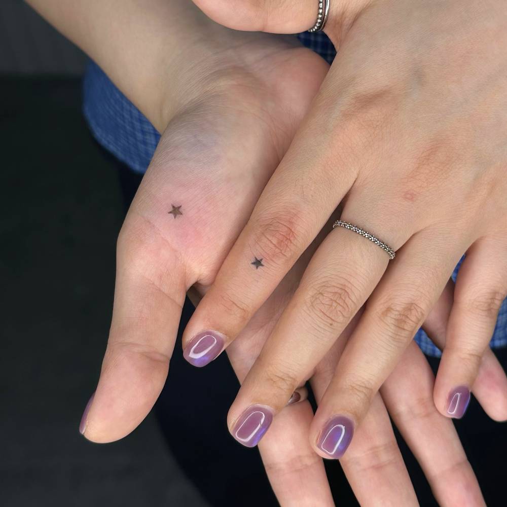 Individual matching hand poked star tattoo in minimalistic style.