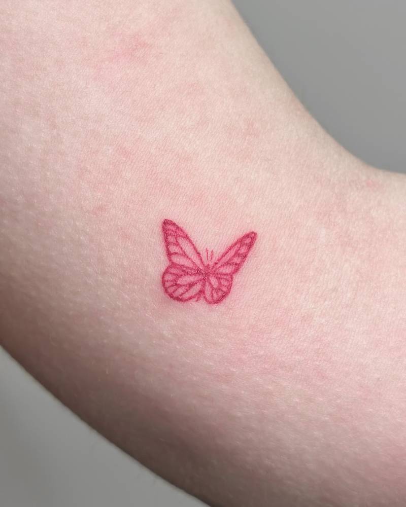 Red butterfly tattoo located on the inner arm.