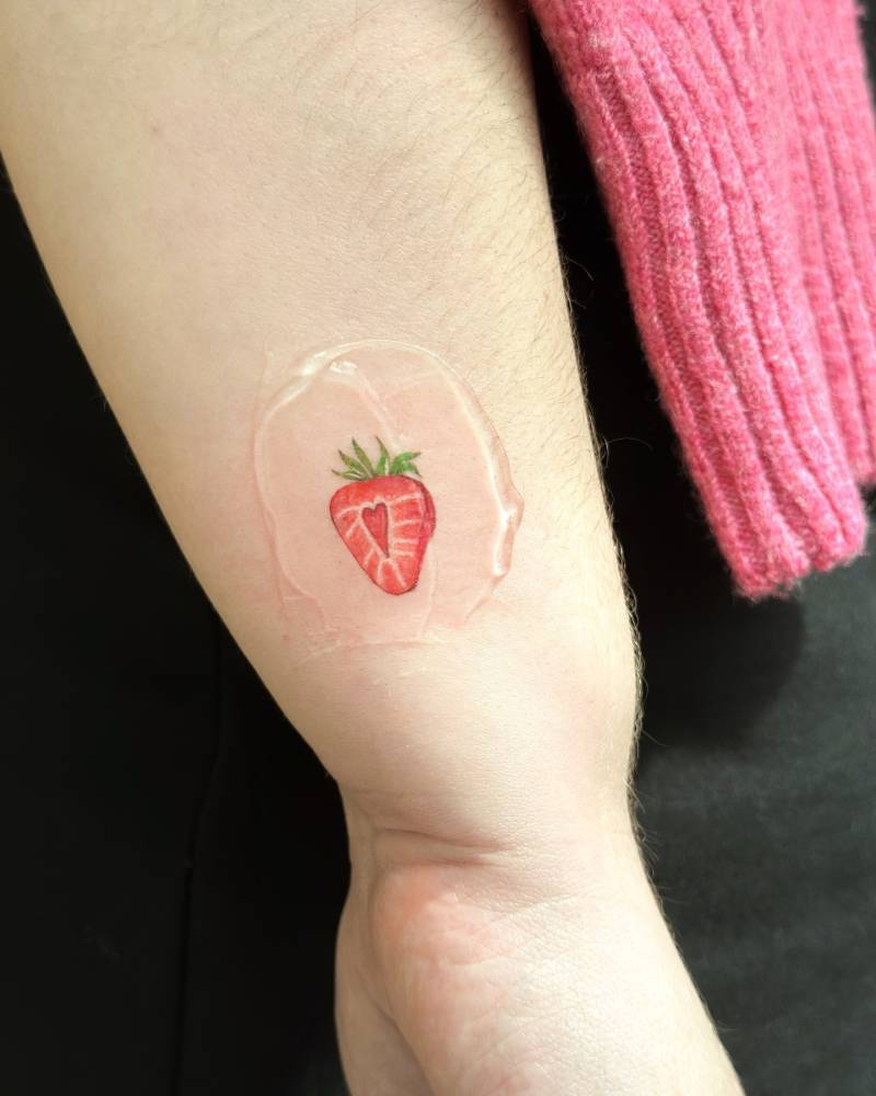 Strawberry tattoo placed on the wrist, done in illustrative style.