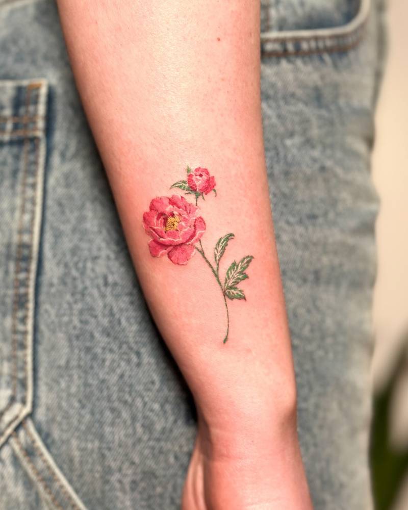 Watercolor style pink peony tattoo located on the wrist.