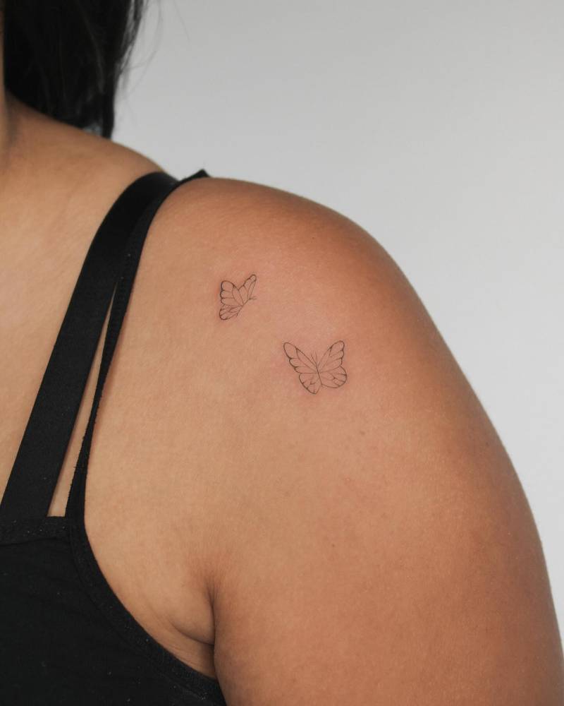 Fine line style butterfly couple tattoo located on the shoulder.