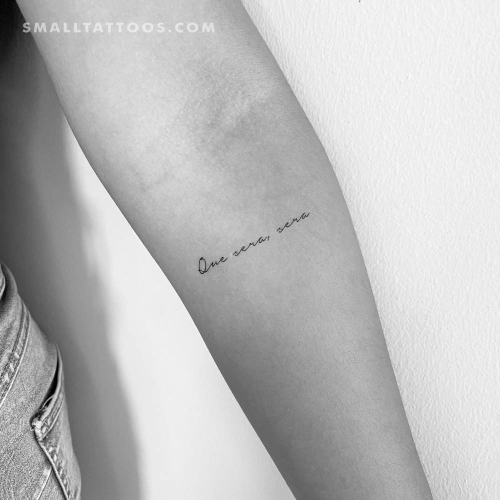 Handwritten font "que sera, sera" temporary tattoo located on the inner forearm.