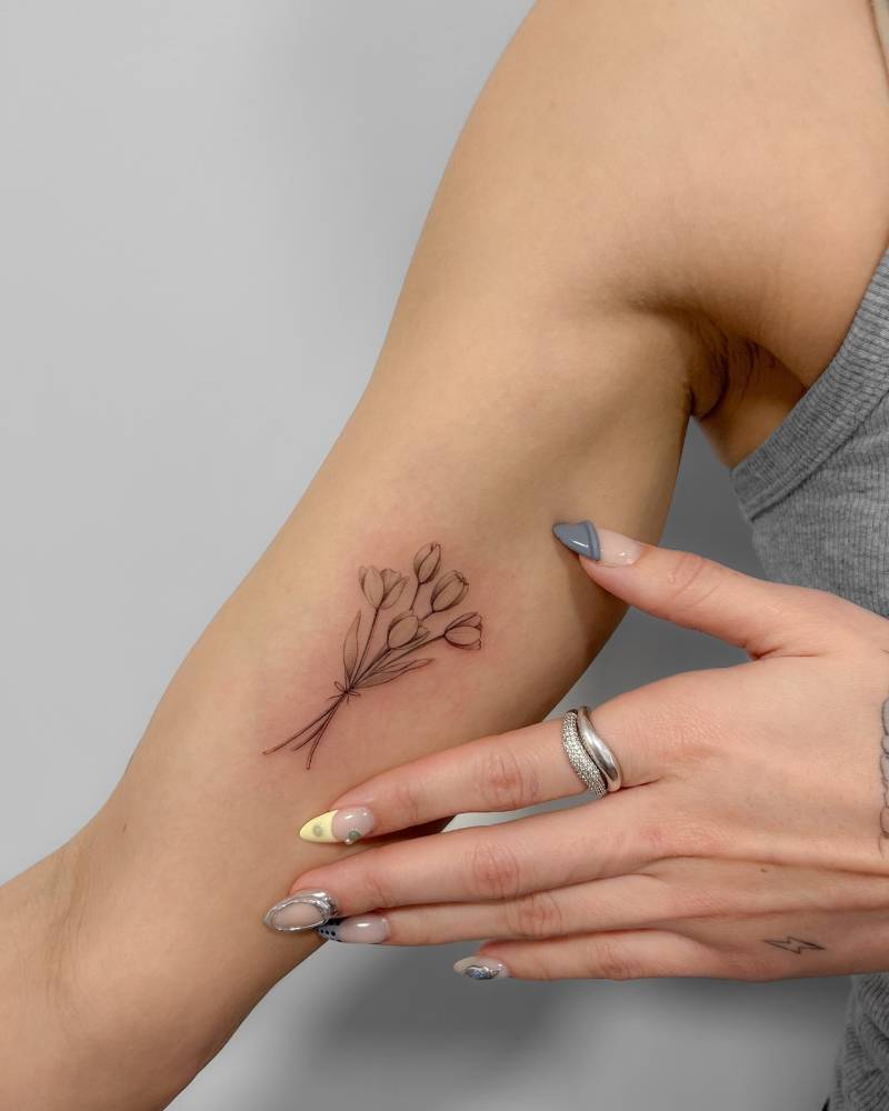 Tulips bouquet tattoo in illustrative style located on the inner arm.