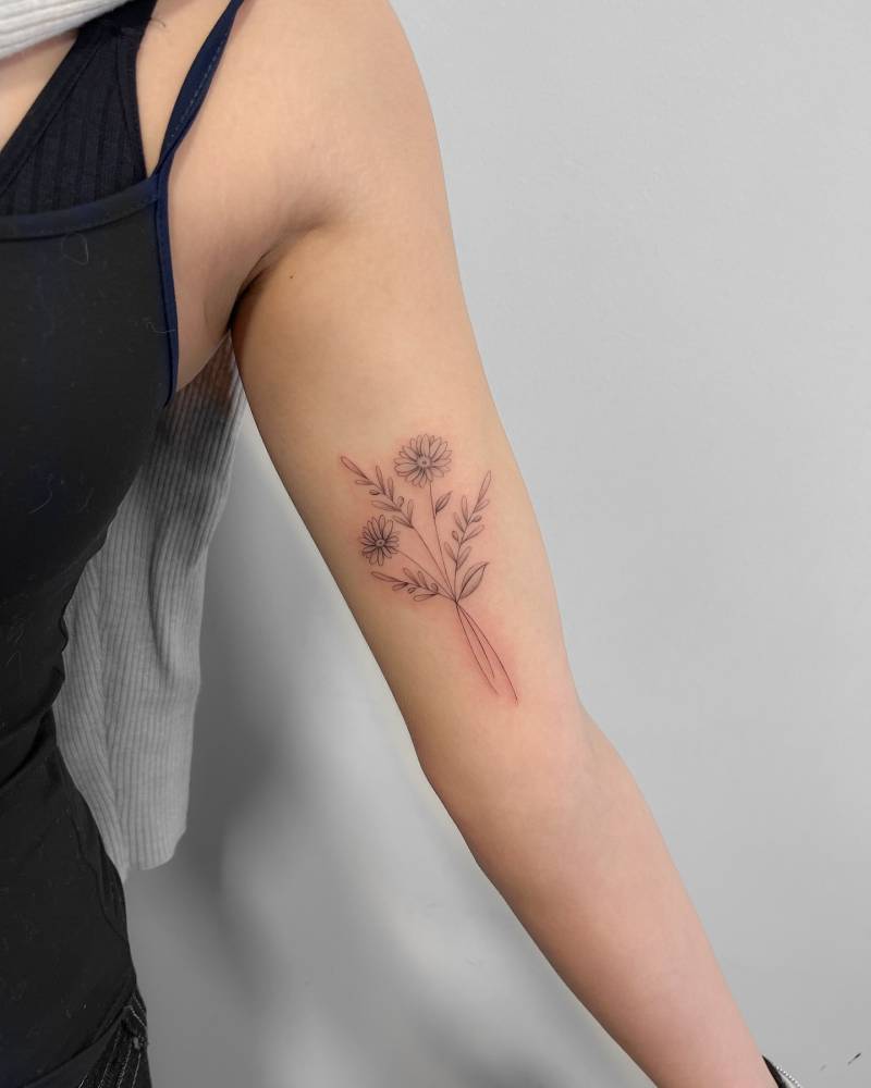 Flower bouquet tattoo placed on the inner arm, done in illustrative style.