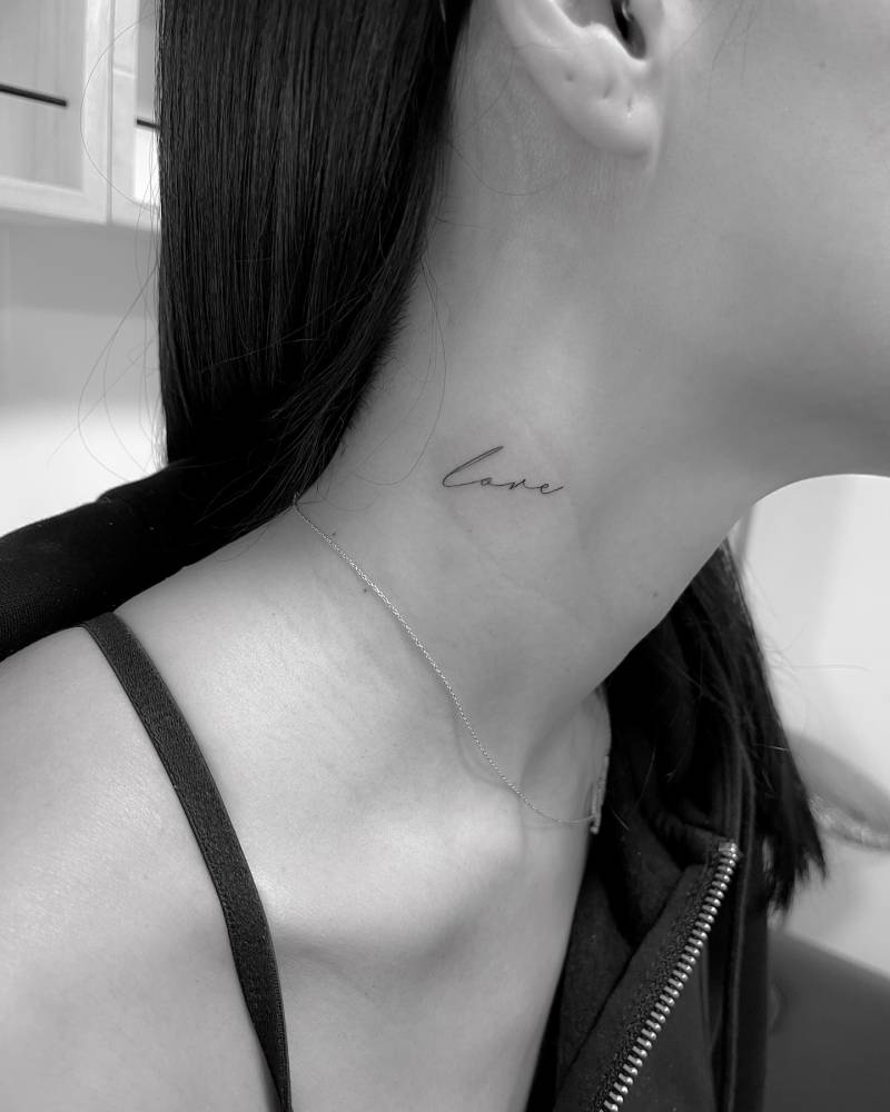 Lettering tattoo of the word "love" located on the neck.