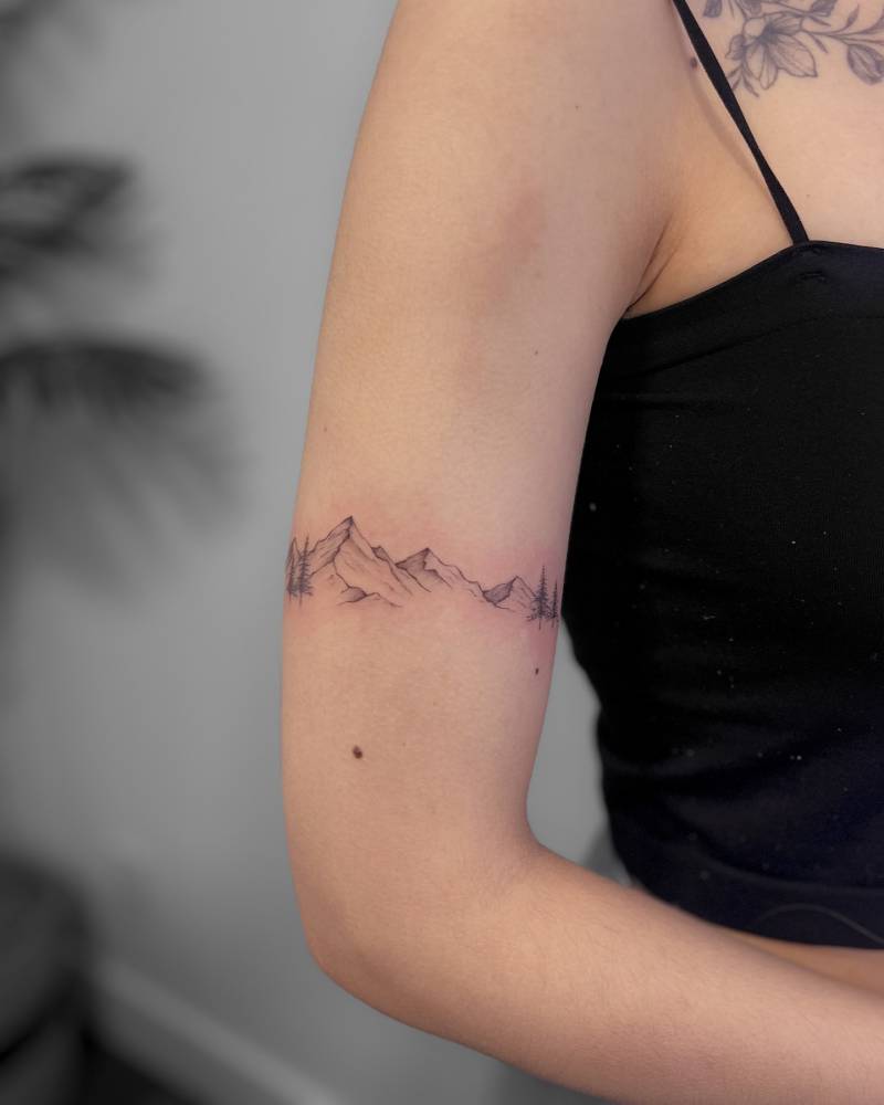 Illustrative style mountains tattoo located on the upper arm.