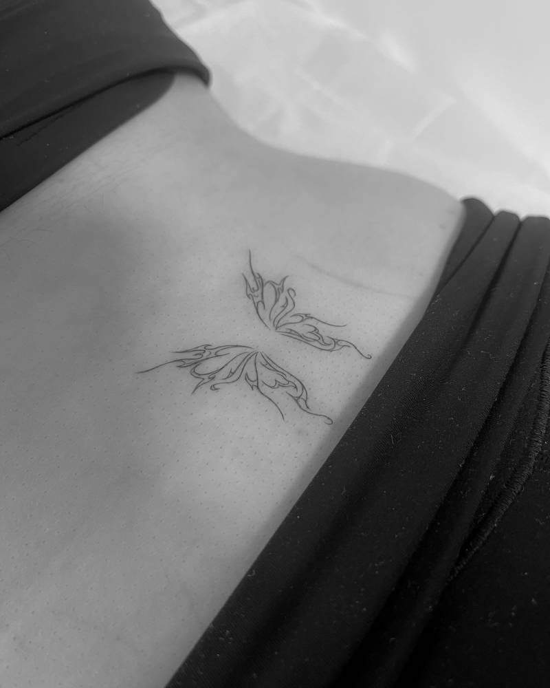 Butterfly wings tattoo in fine line style located on the lower back.