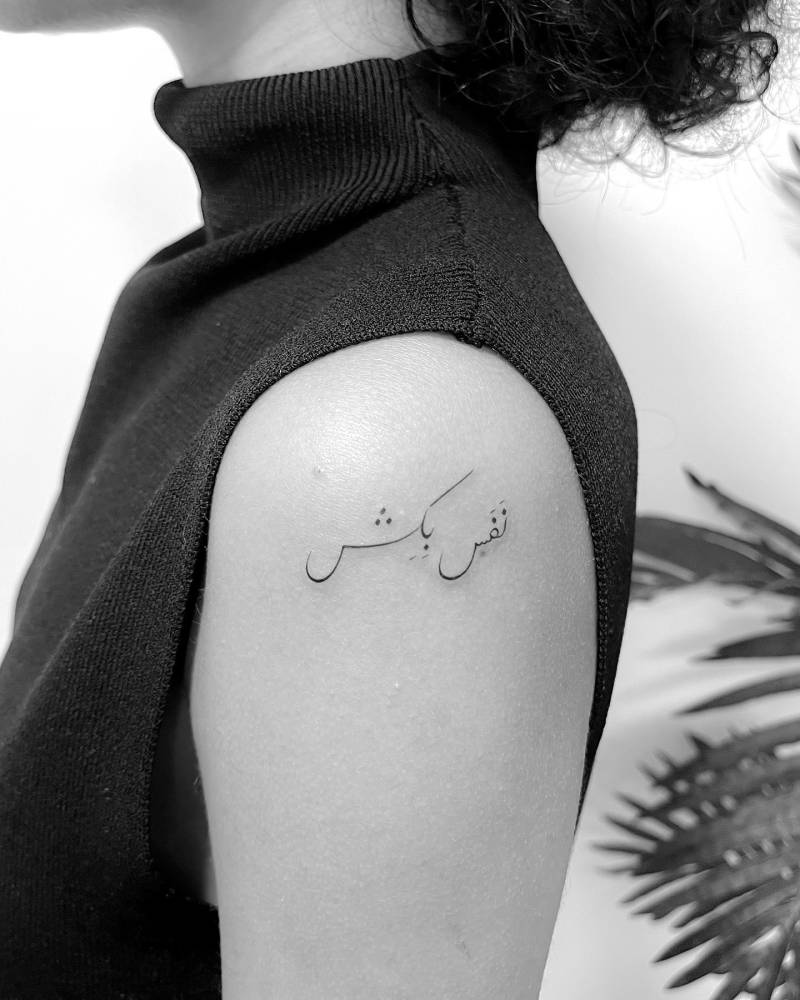 Arabic lettering tattoo located on the shoulder.