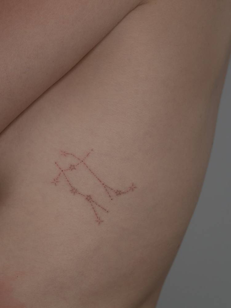 Minimalistic style Gemini constellation tattoo located on the side boob.