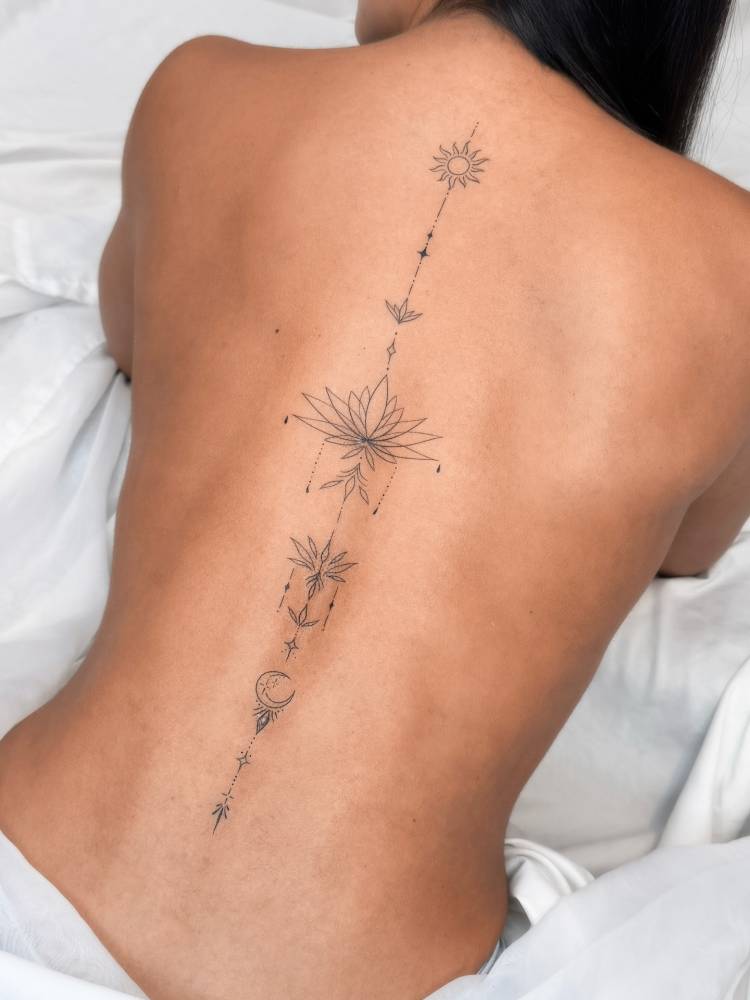 Fine line style symbol chain tattoo located on the spine.