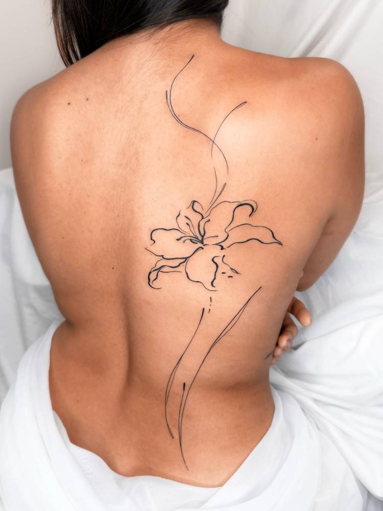 Line art style lily flower tattoo placed on the back.