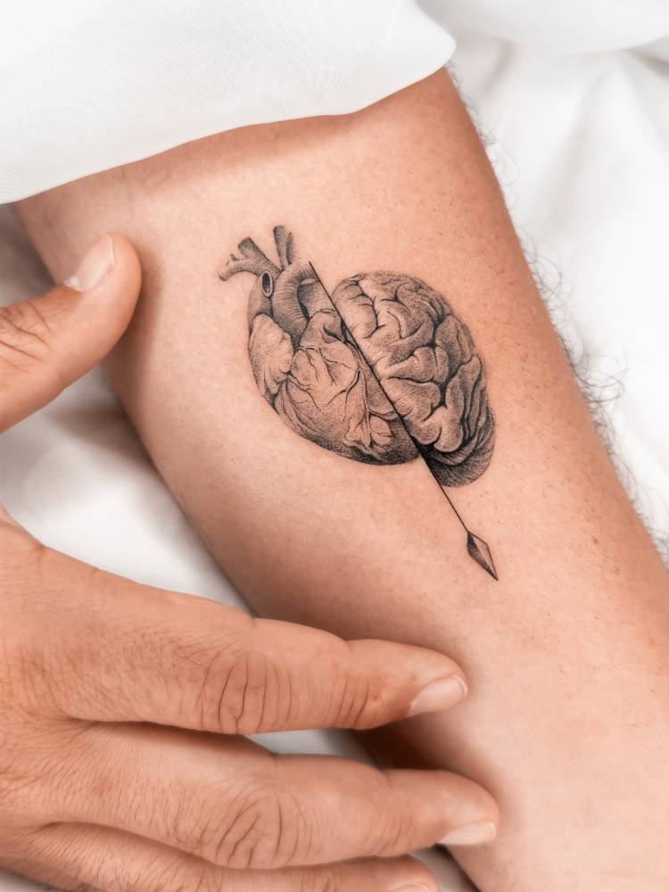 Heart vs brain tattoo in micro-realistic style located on the inner forearm.