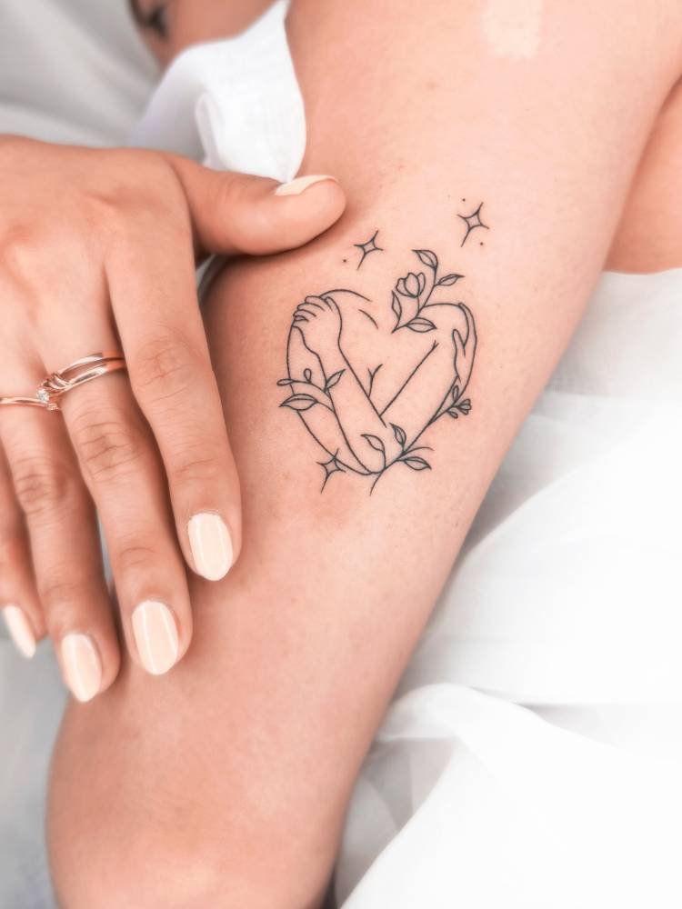 Self hug tattoo in fine line style located on the upper arm.