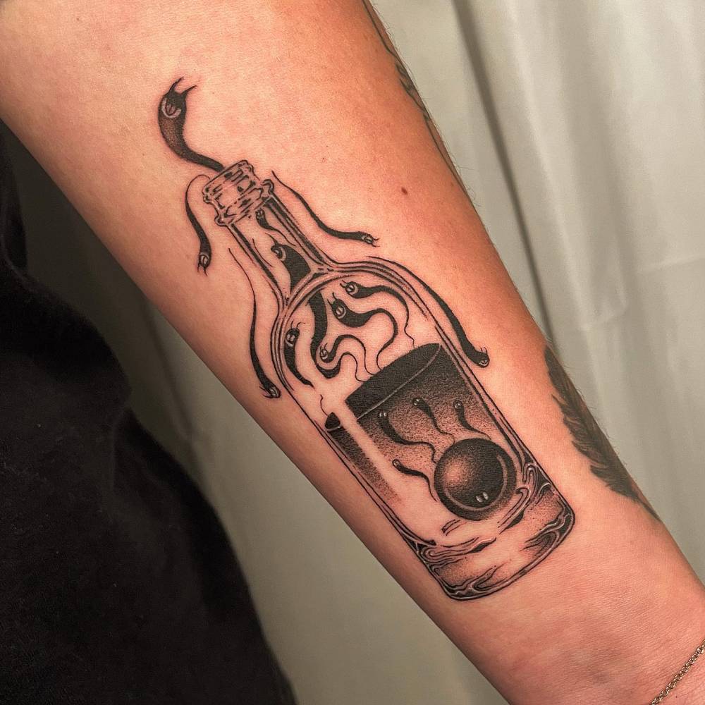 Blackwork style poison bottle tattoo located on the inner forearm.