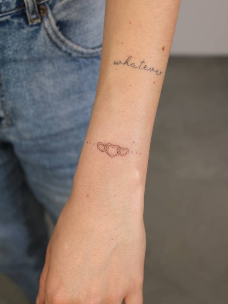 Heart chain tattoo in fine line style located on the wrist.