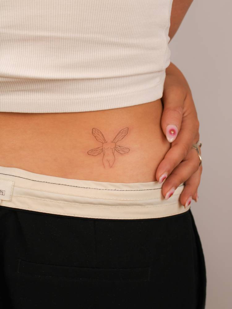 Fairy tattoo in fine line style located on the lower back.