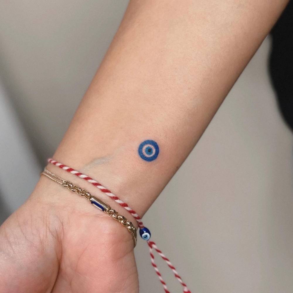 Tiny Nazar tattoo located on the wrist, done in minimalistic style.