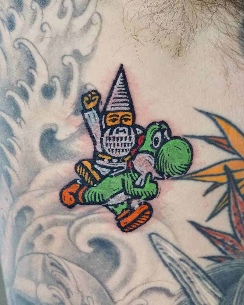 Gnome riding Yoshi tattooed on the rib, cartoon style.