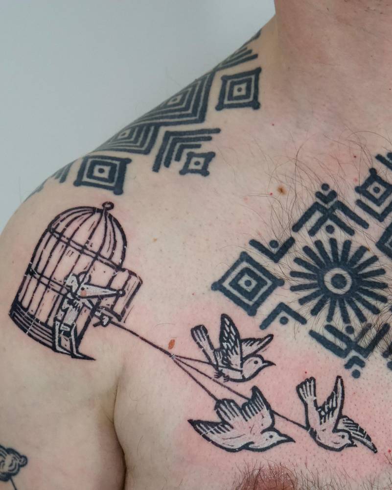 Pop art style doves flying a mouse in a bird cage tattooed on the shoulder and chest.