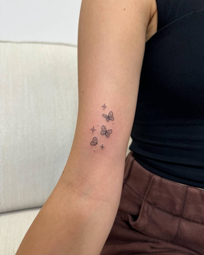 Fine line style little butterflies tattoo placed on the bicep.