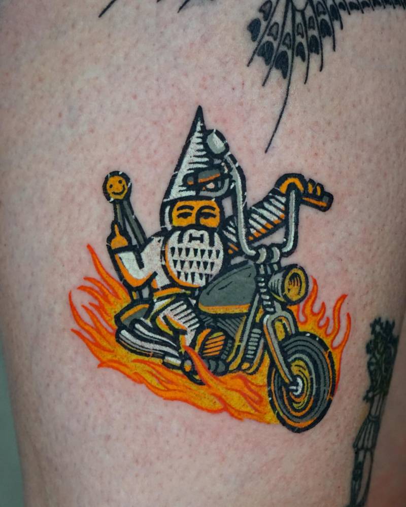 Gnome riding a motorbike tattooed on the thigh.