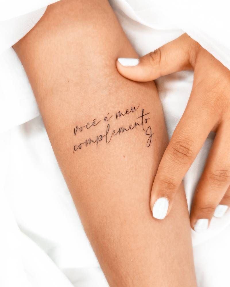 "Você é o meu complemento" lettering tattoo located on the inner forearm.