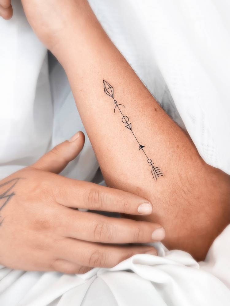 Fine line style arrow tattoo located on the forearm.