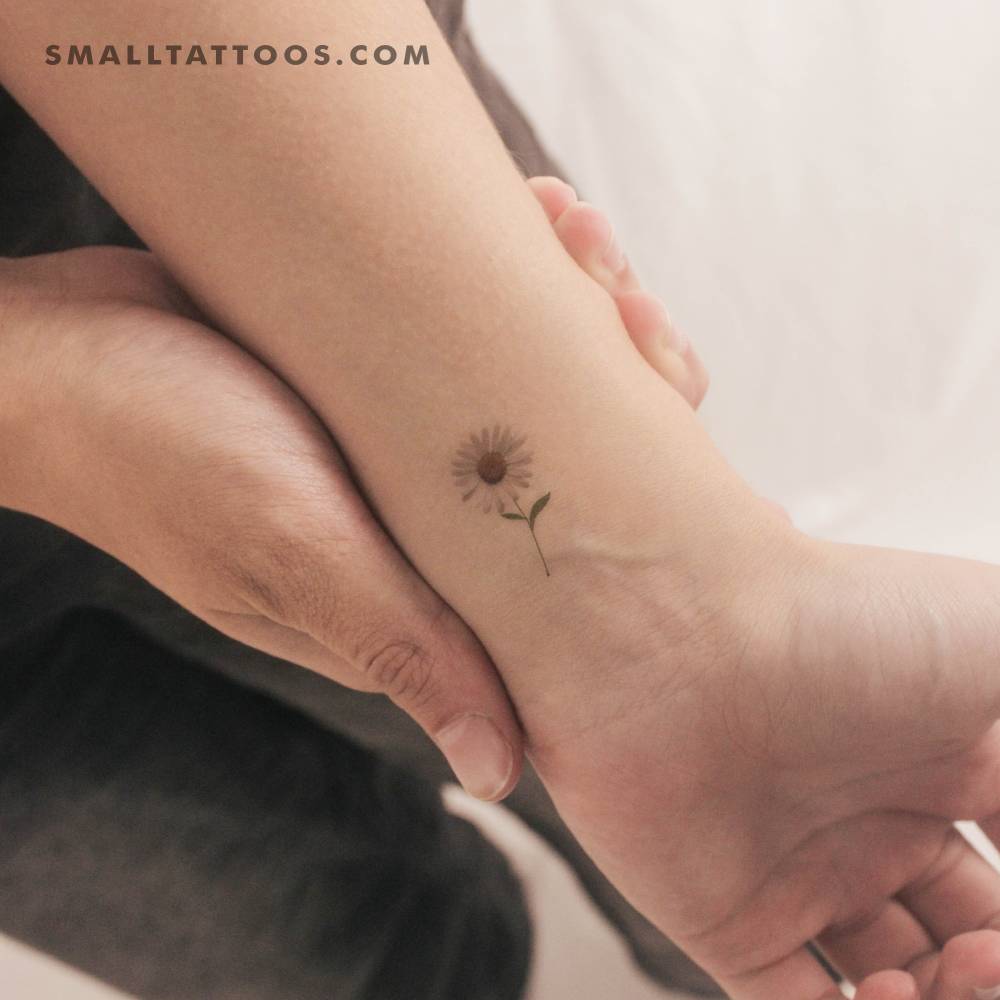 Small watercolor style daisy temporary tattoo located on the wrist.
