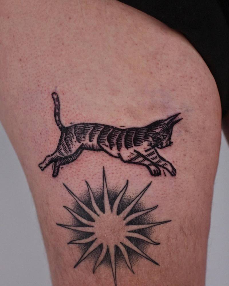 Cat tattoo in engraving style located on the thigh.
