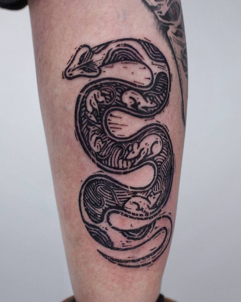 Engraving style snake tattoo placed on the calf.