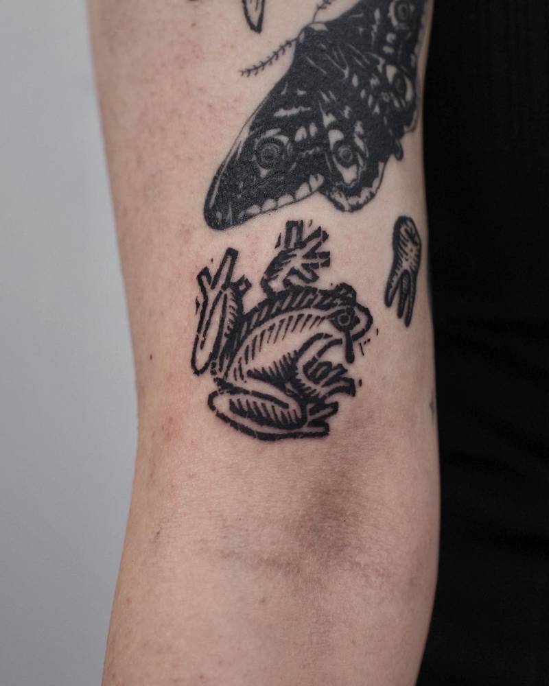 Frog tattoo in blackwork style placed on the bicep.