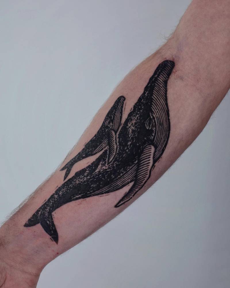 Whales tattoo in blackwork style located on the inner forearm.