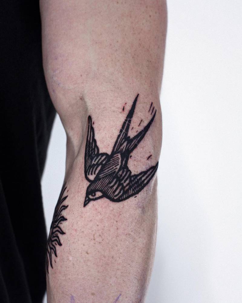 Swallow tattoo in engraving style located on the elbow.