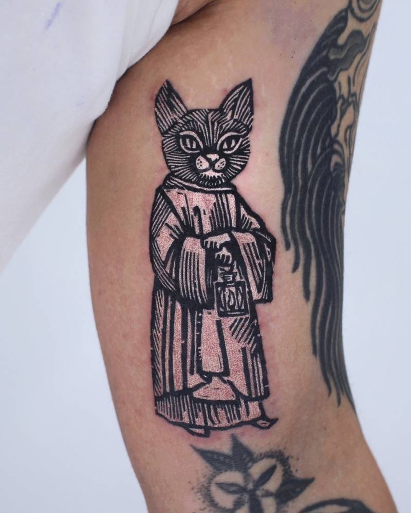 Pop art style priest cat tattoo placed on the inner arm.