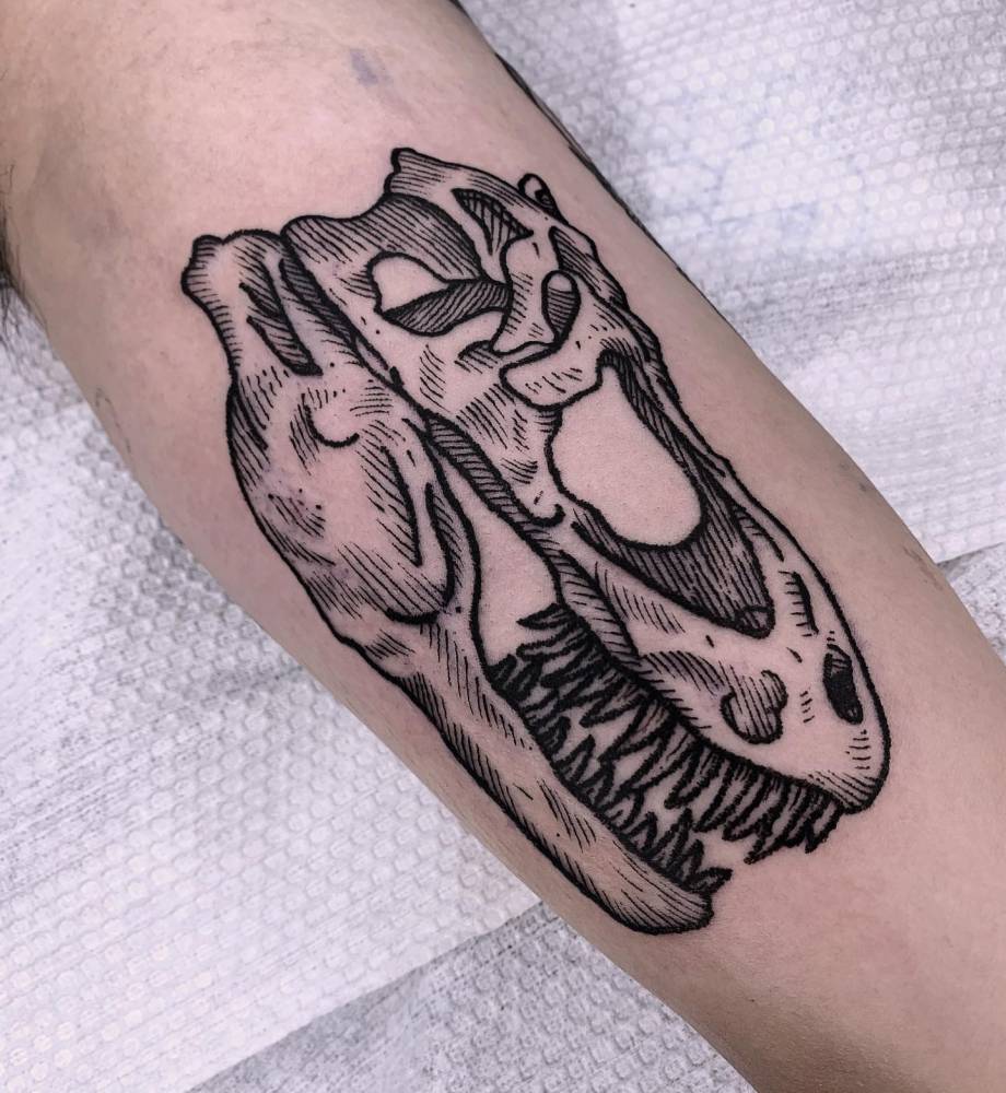 T-rex skull tattoo in blackwork style placed on the inner arm.