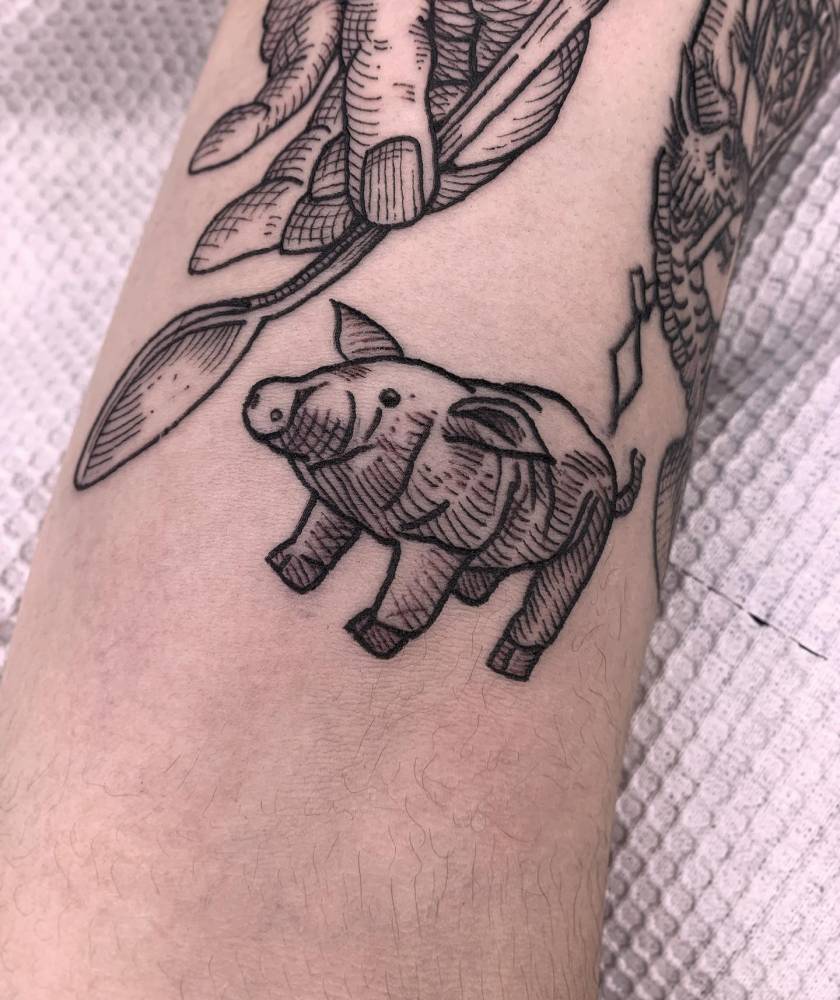 Little pig tattoo in blackwork style located on the bicep.