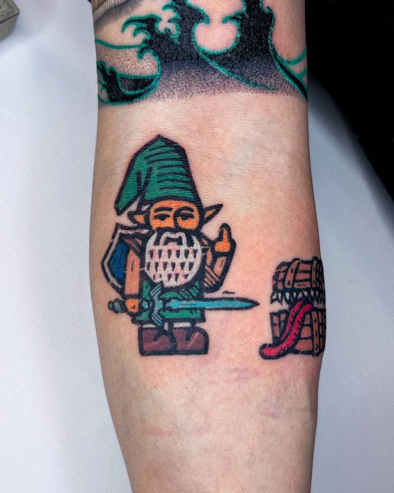 Cartoon style Link gnome tattooed on the inner forearm.