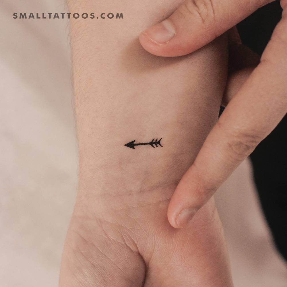 Tiny minimalistic arrow temporary tattoo placed on the wrist.