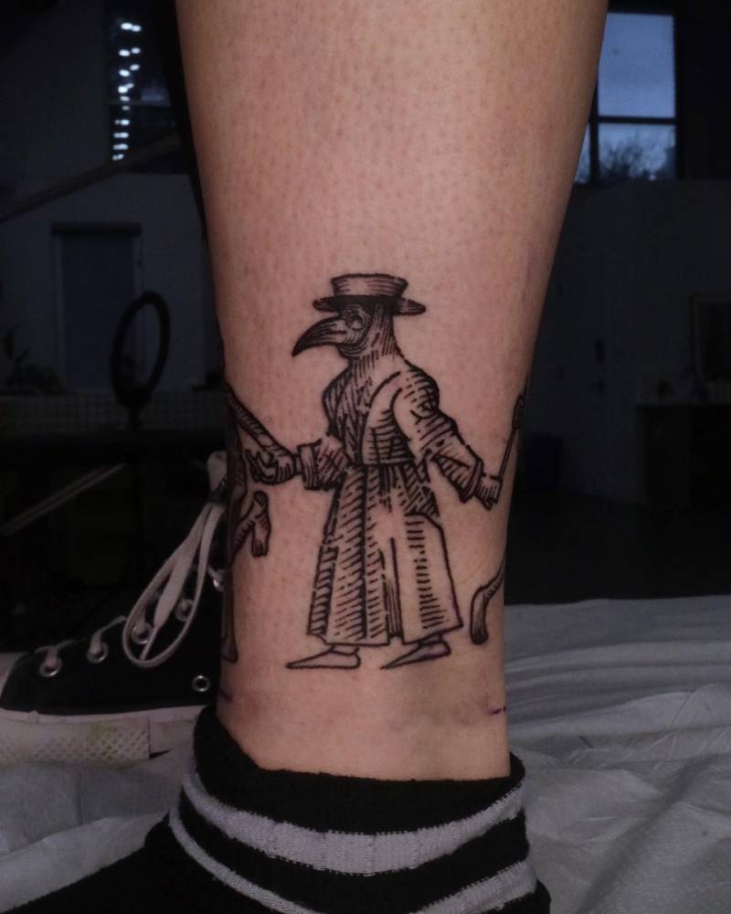 Engraving style plague doctor tattoo located on the ankle.