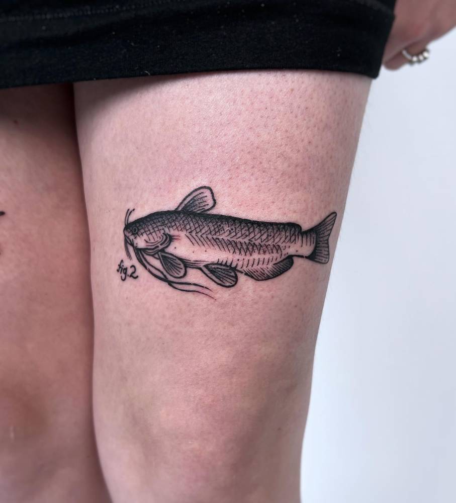 Catfish tattoo in engraving style located on the thigh.