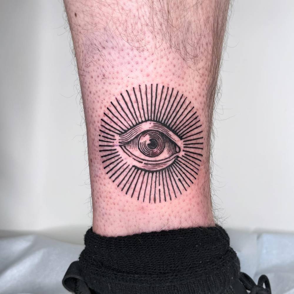 Eye tattoo located on the ankle, done in engraving style.