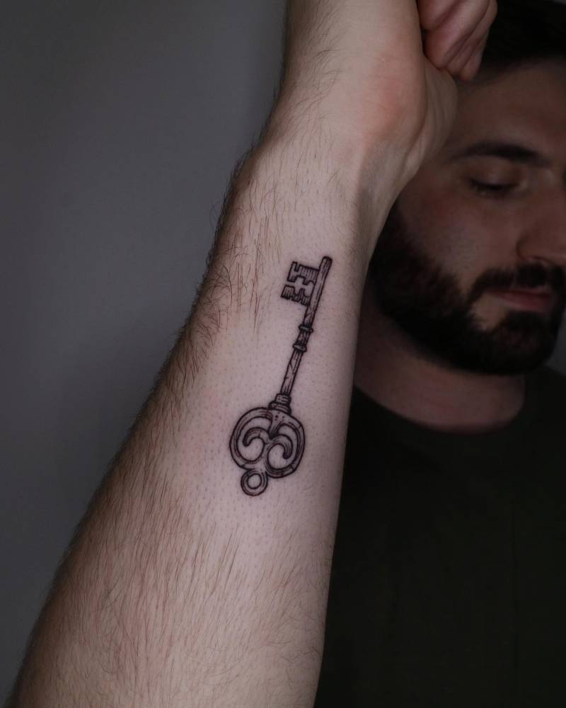 Key tattoo in blackwork style located on the wrist.