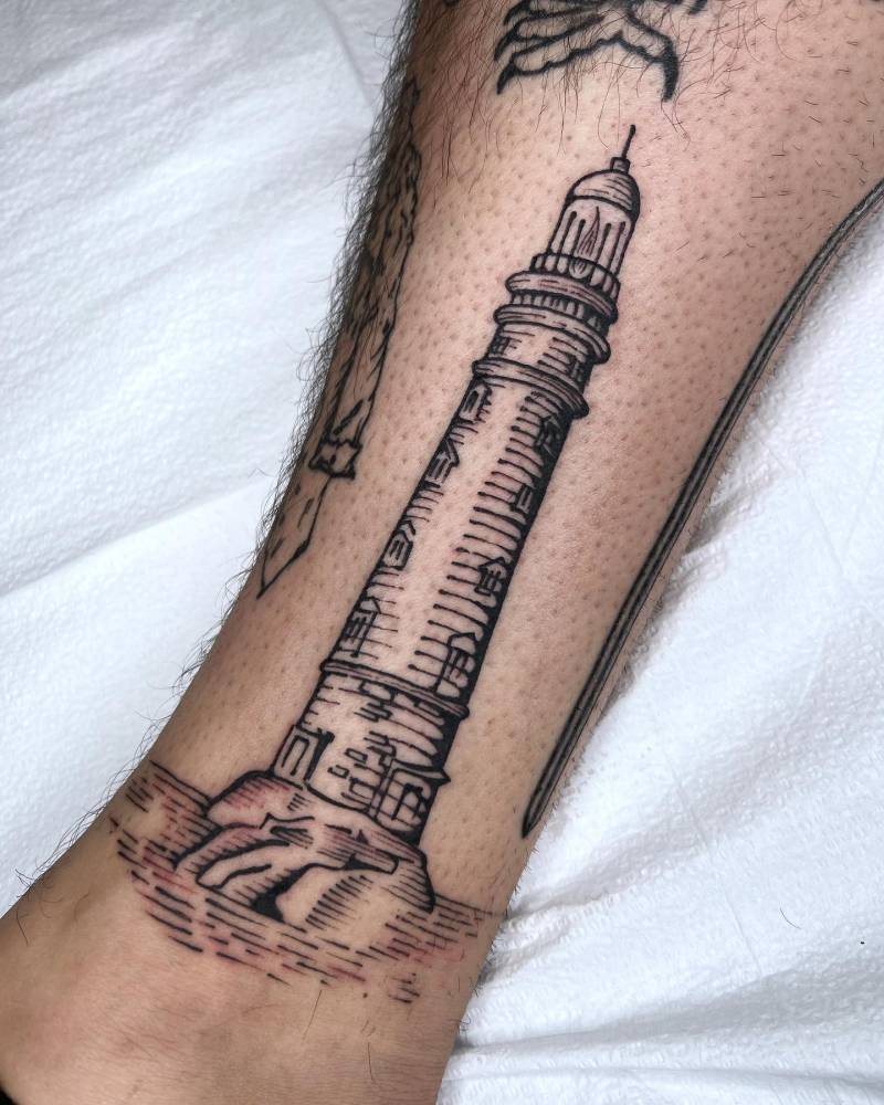 Lighthouse tattoo located on the shin, done in engraving style.