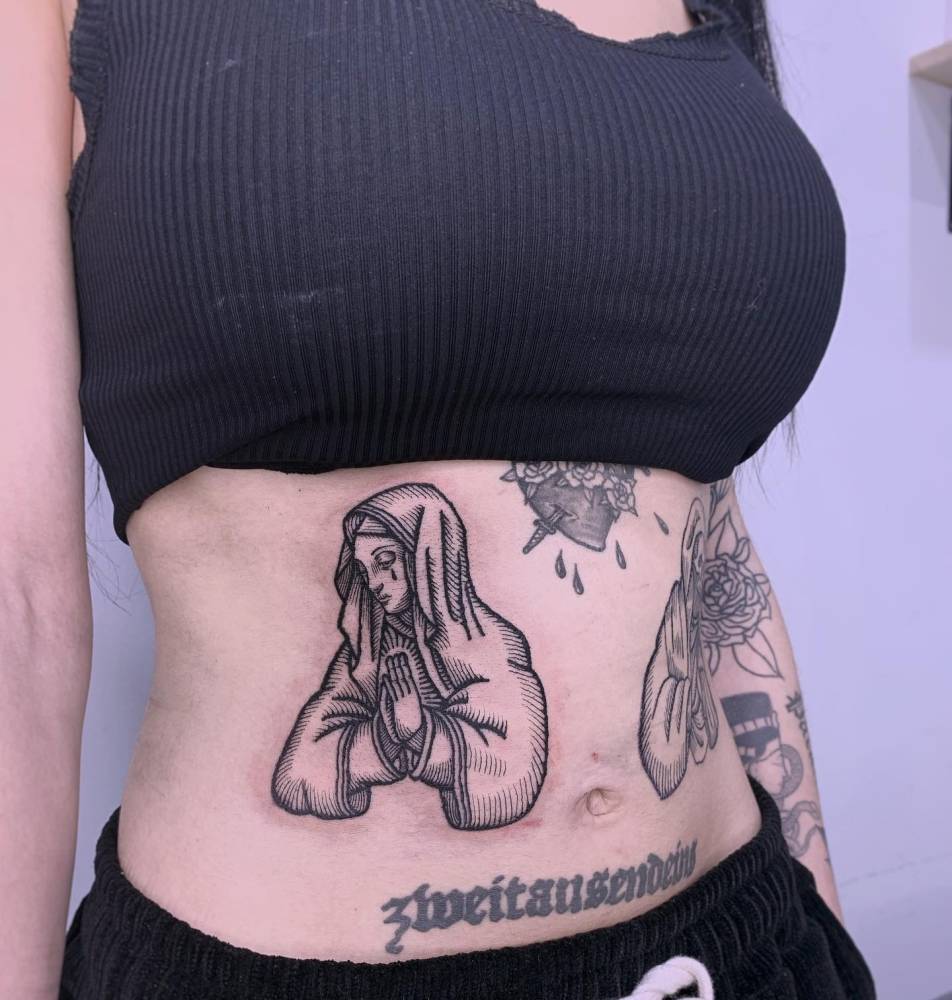 Engraving style Virgin Mary tattoo located on the waist.