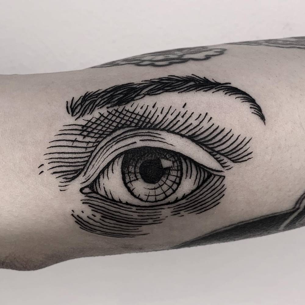Eye tattoo in engraving style placed on the inner forearm.