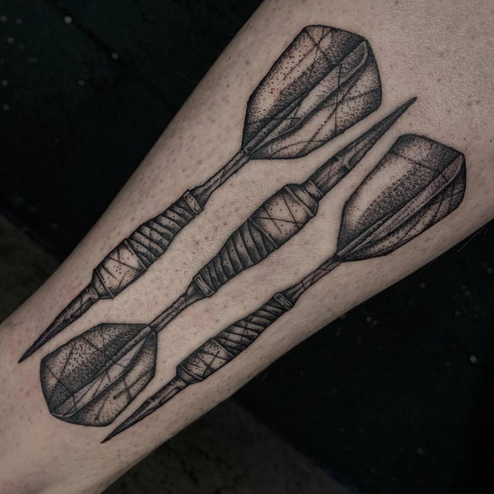 Darts tattoo in blackwork style placed on the inner forearm.