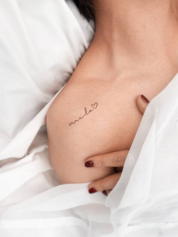 Handwritten font name "Mila" tattooed on the shoulder.