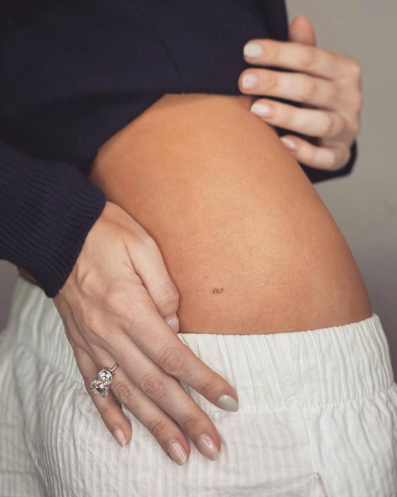 Minimalistic style Scorpio zodiac symbol tattooed on the lower back.